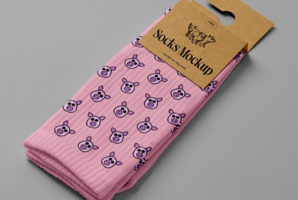 View from above, pink pair of socks mockup with a craft paper label attached to it, laying on the gray floor.