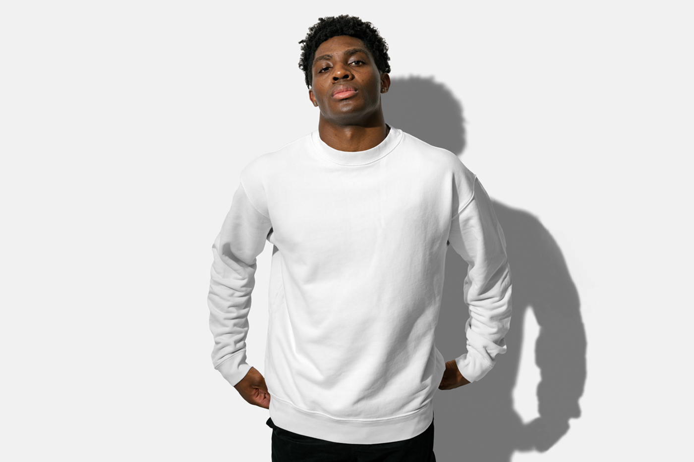 Standing men wearing white sweatshirts in front of the white wall.