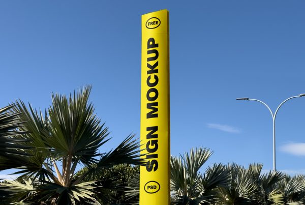 Front view, yellow vertical sign mockup standing between trees.