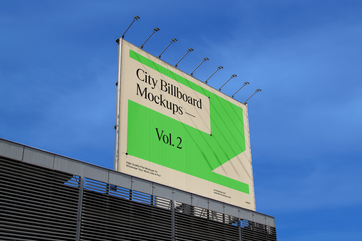 A horizontal city billboard mockup attached to the roof of the building, with the clean blue sky in the background.
