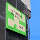 Big square city billboard mockup with bright beige, green design and green coffer attached to the building elevation.