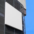 A big white square city billboard mockup with a white coffer attached to the building elevation.