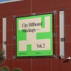 Two square city billboard mockups with a black, green design attached to the red-colored building elevation wall.