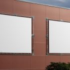 Two white square city billboard mockups attached to the red-colored building elevation wall.