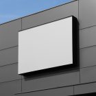 Horizontal white city billboard mockup with black frames attached to the metal gray building facade.