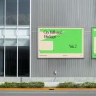 Front view, two horizontal city billboard mockups with bright beige, green design and silver frames attached to the gray building elevation.