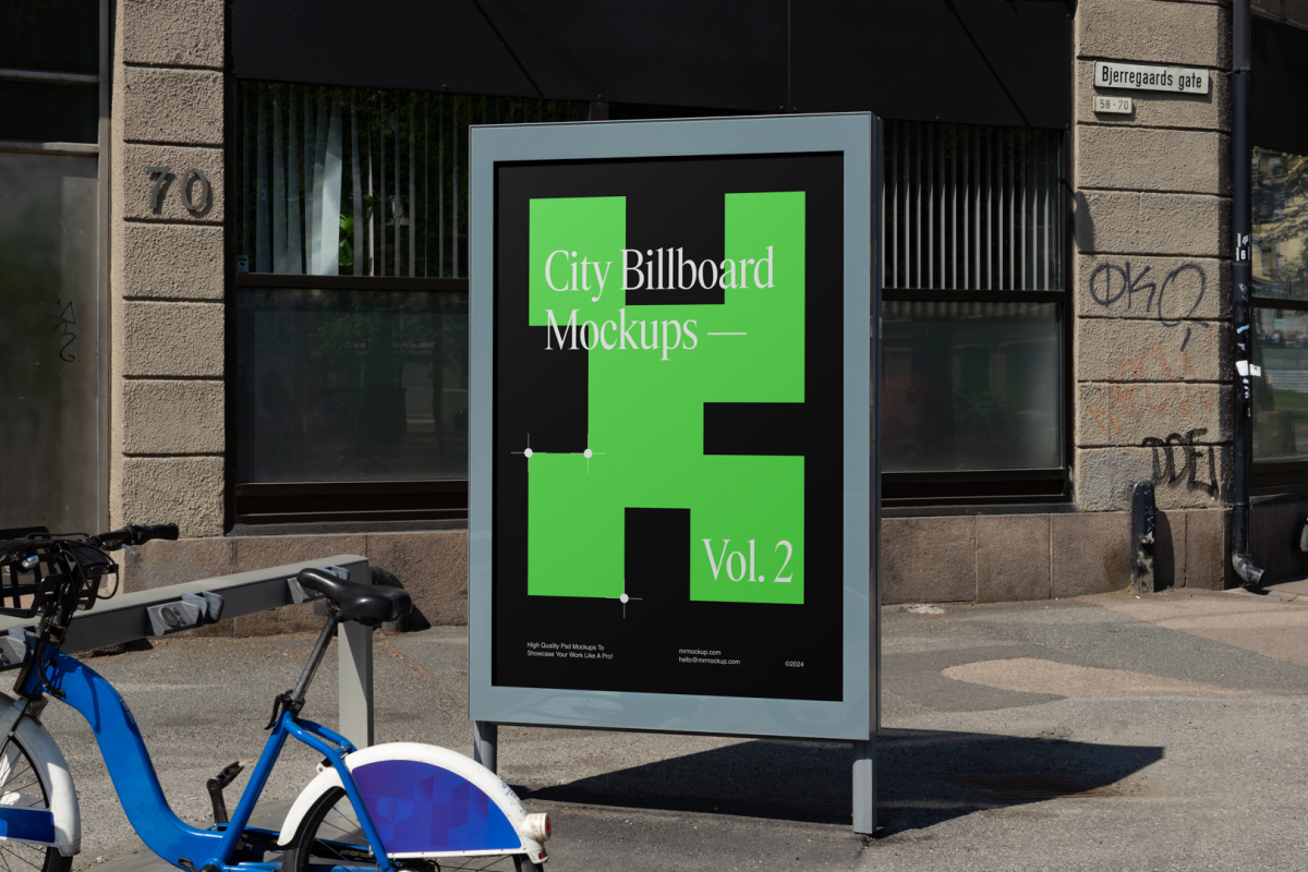 City billboard mockup with green, black design and strong silver frames standing between the buildings in the middle of the city in the background.