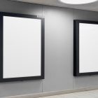 Two vertical white billboard mockups with strong black frames attached to the gray wall.