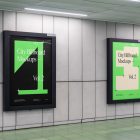 Two vertical city billboard mockups with green and black design and black strong frames attached to the gray wall.