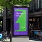 City light billboard mockup standing pedestal between the buildings in the middle of the city in the background.