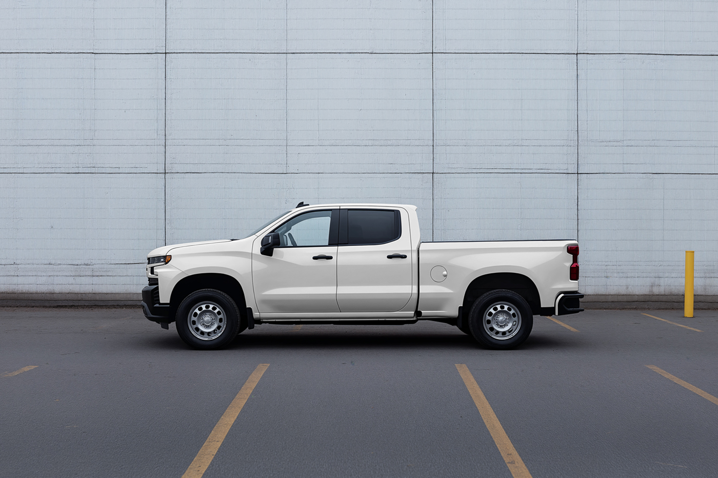 Front view, white pickup truck mockup standing on the parking in front of the bright blue wall.