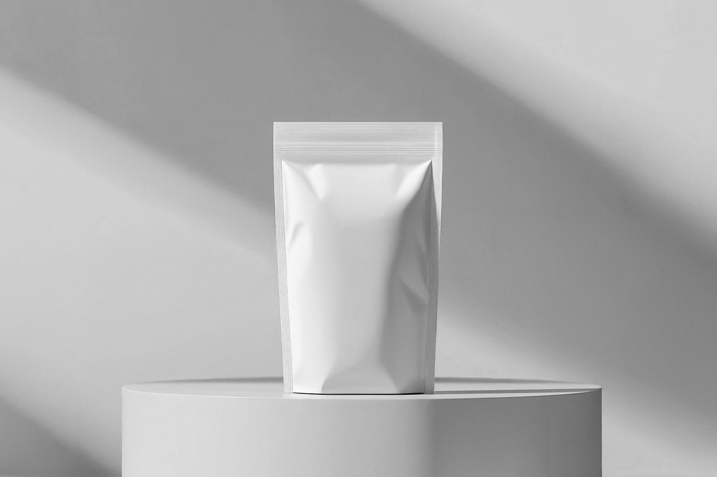 Front view, white plastic coffee bag mockup standing on the white cubic in front of the white wall.