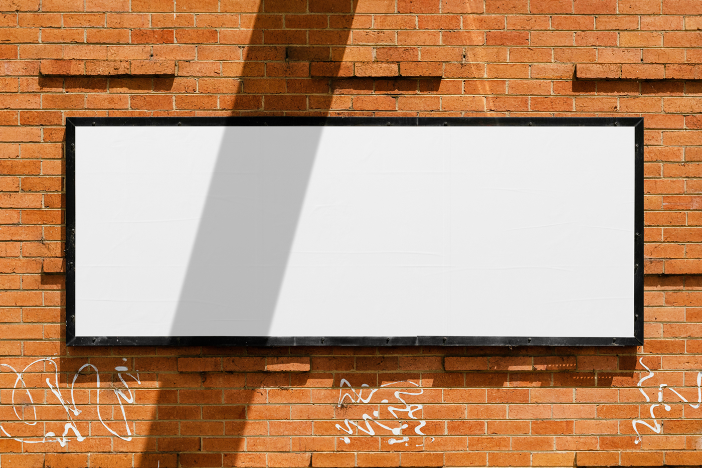 Front view, horizontal white billboard with a black frame attached to the brick wall.