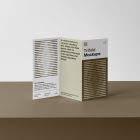 Front view, of a standing Trifold Mockup on a brown box where for is a white wall.