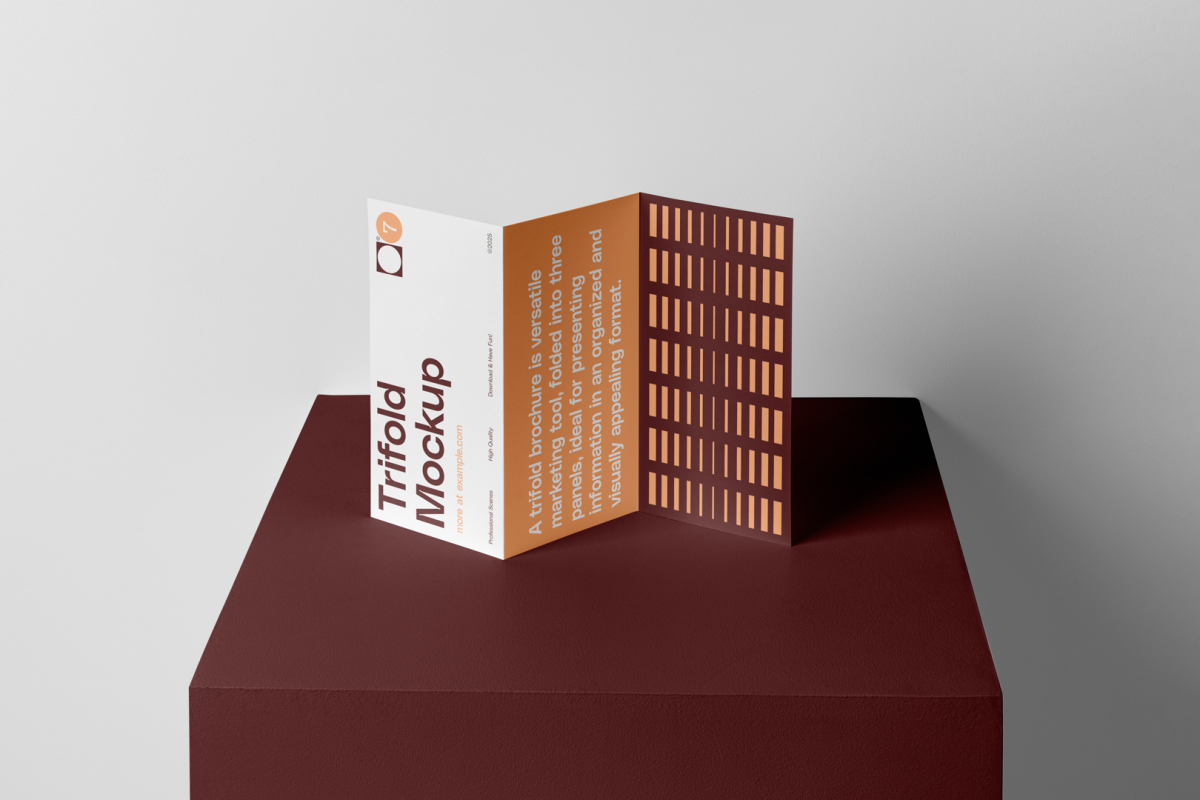 Front view, from above, with a little angle of single standing on a dark claret box Trifold Mockup arranged in the letter z. Behind the claret box is a huge white wall.