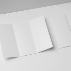 View from above, at a 45-degree angle of a two white Trifold Mockups laying on a white box.