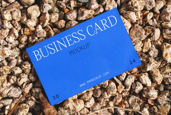 View from above, laying blue business card mockup on pebbles.