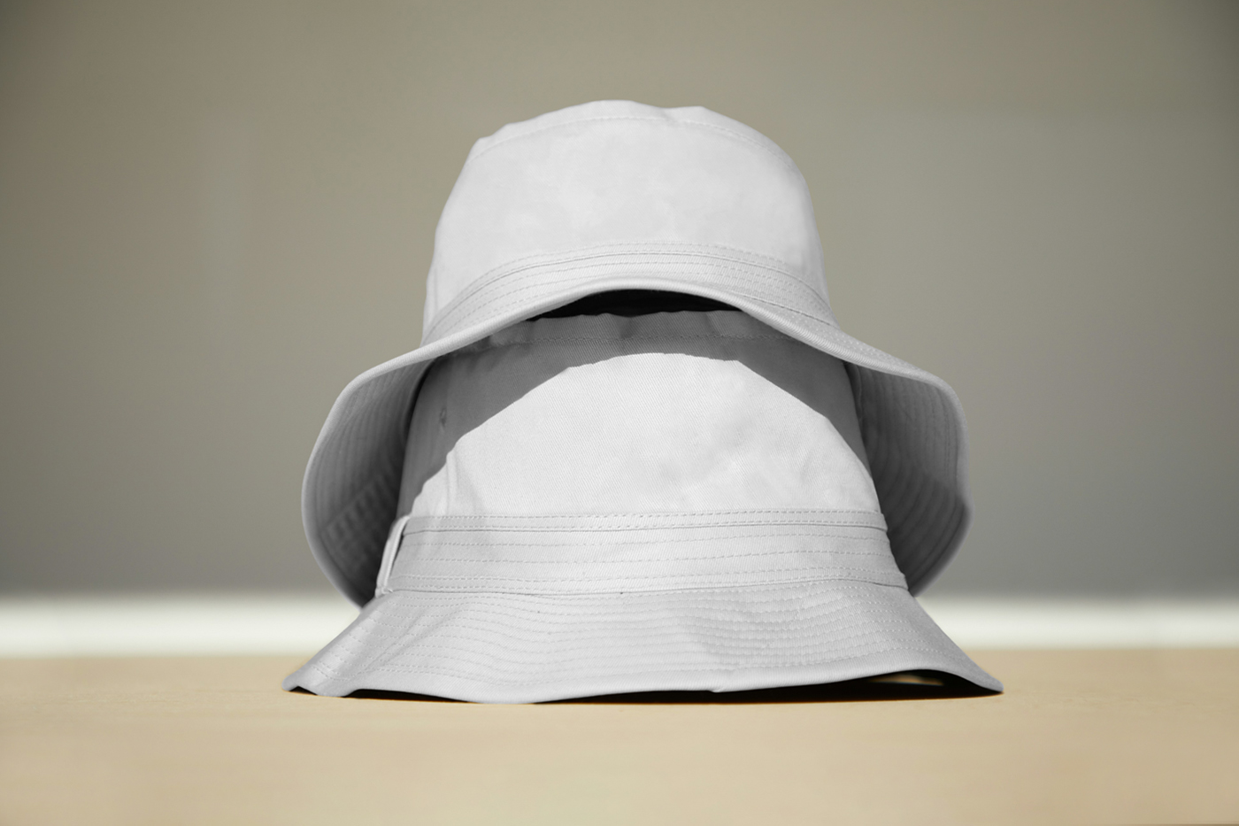 Front view, two white bucket hat mockups stacked on top of each other laying on the floor.