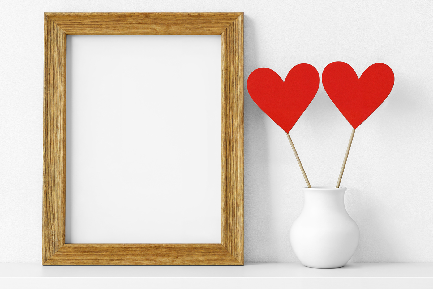 Front view, blank Valentine's Day Frame Mockup standing on the white floor based on white wall right next to a standing white vase on the right side.