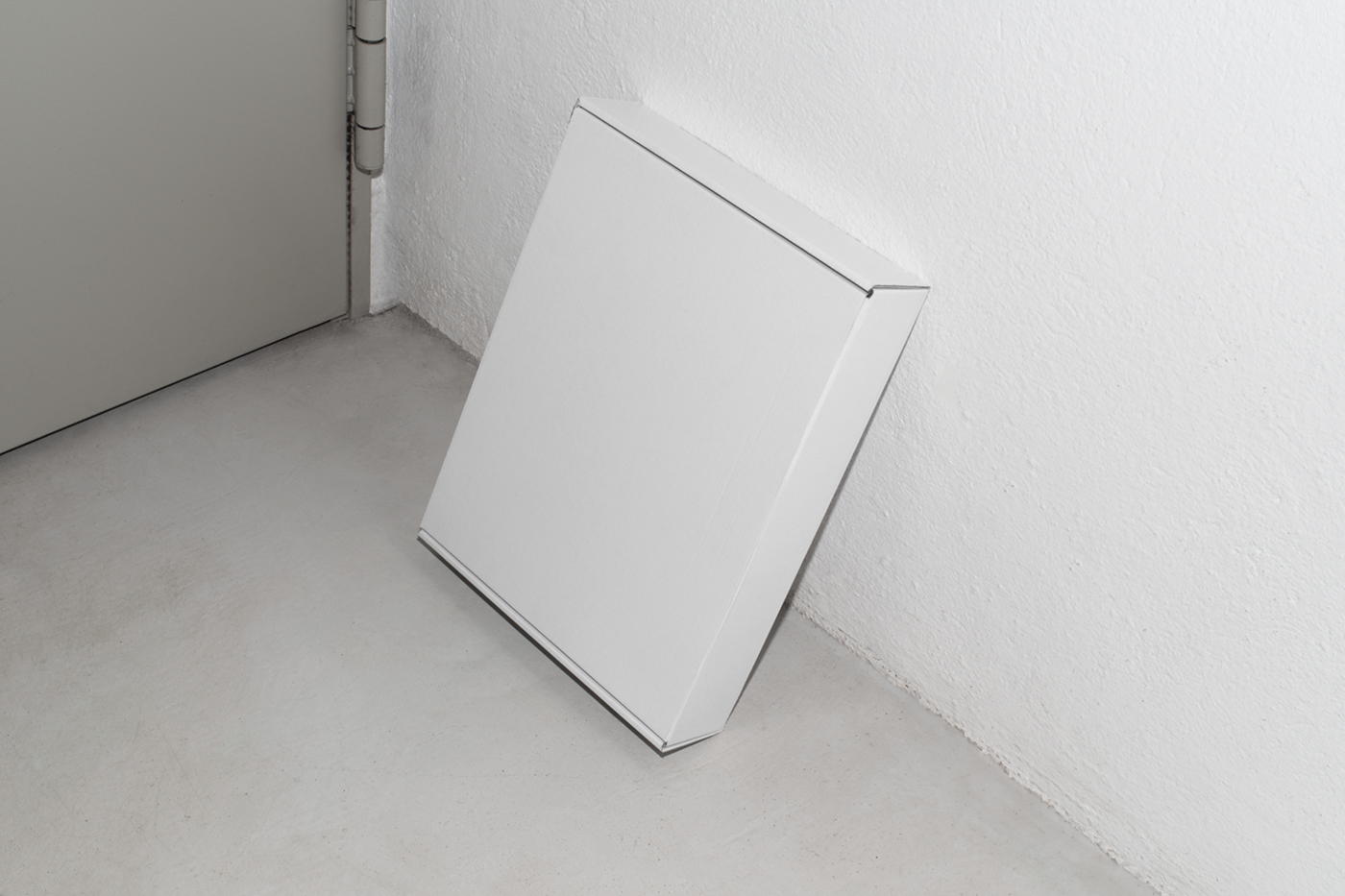 View from above of a white box mockup based on a white wall.