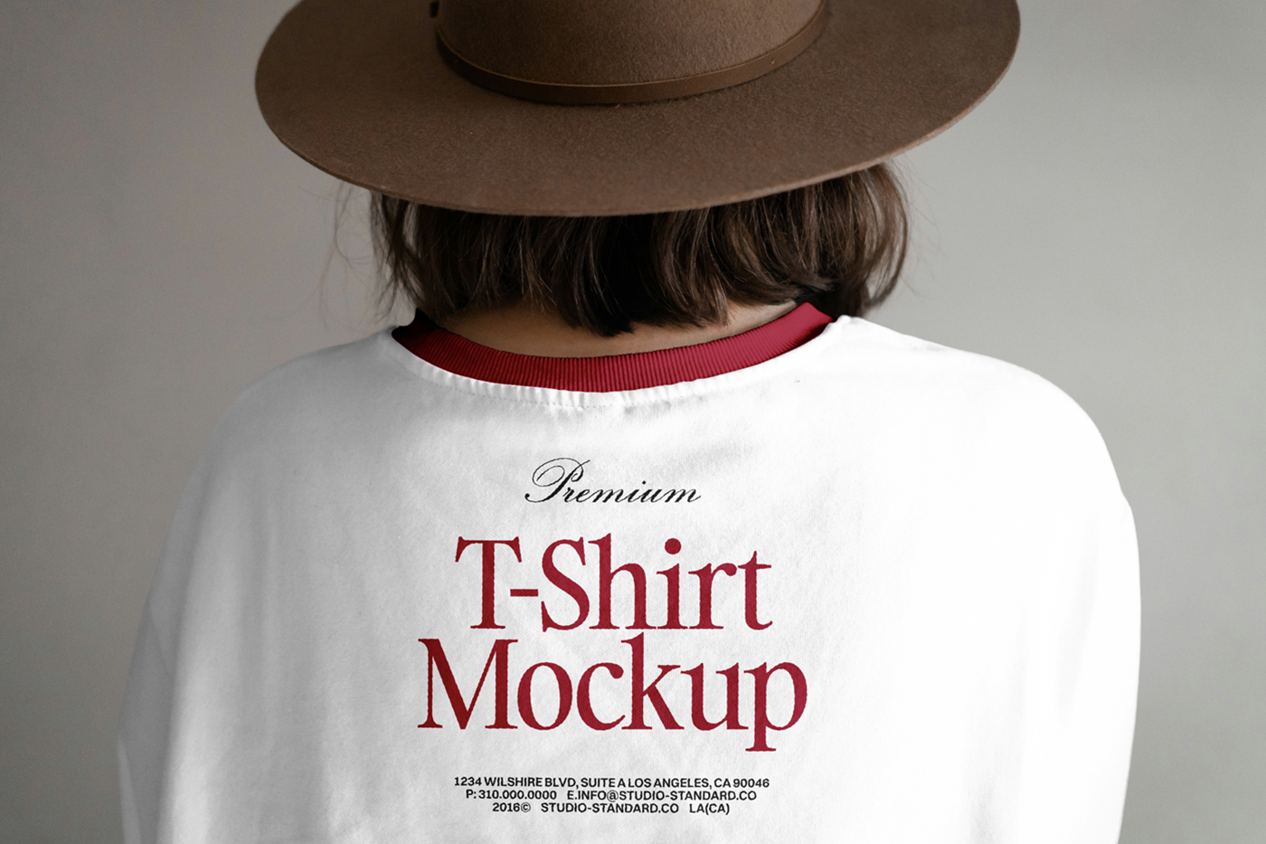 Front view, standing woman backwards wearing t-shirt mockup with typography design right in front of the gray wall.