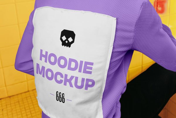 A man sitting on a wall with his back to the lens wearing a hoodie mockup with typography design between dirty space area.