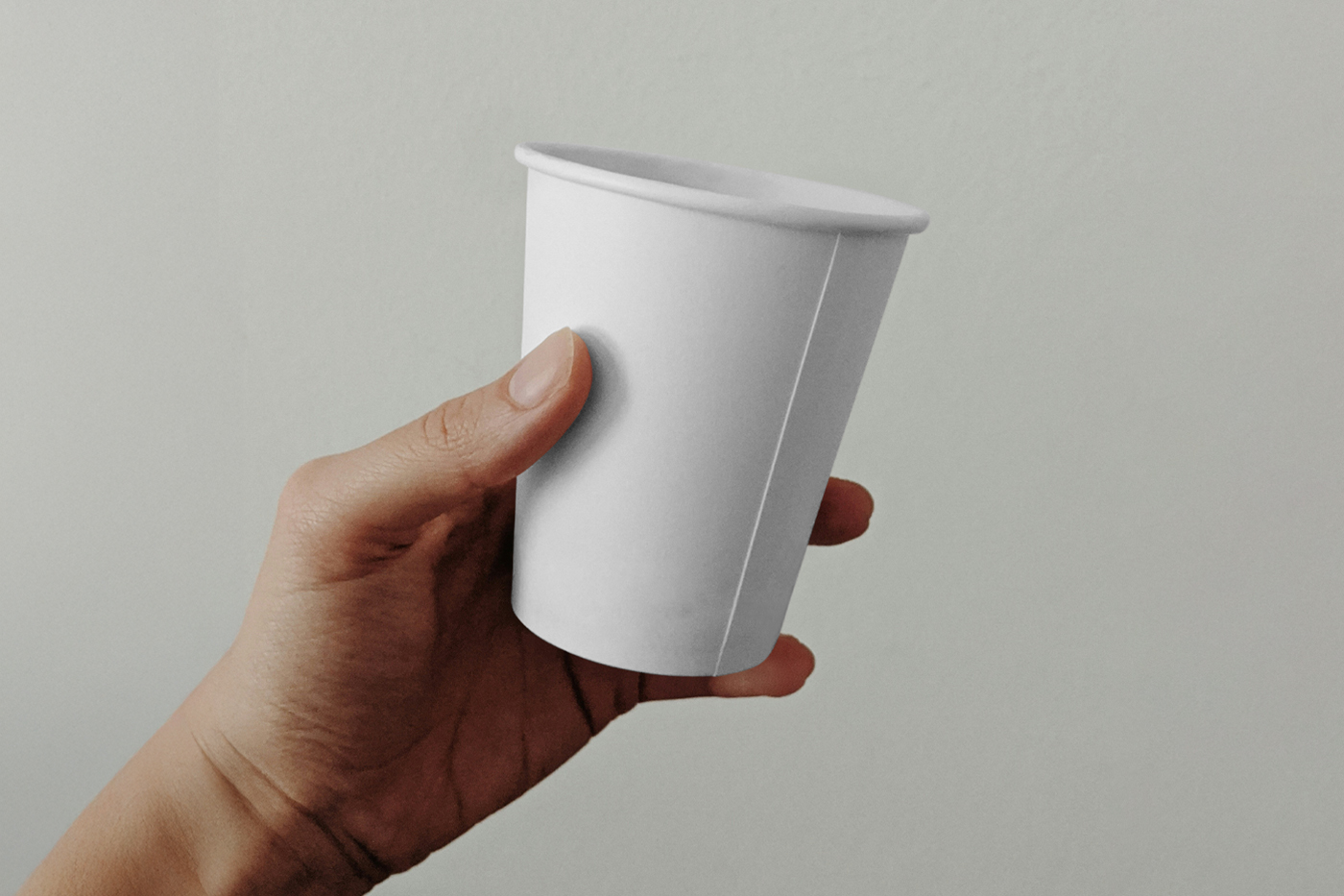 Front view, a man holding a white coffee cup mockup with a bright green color wall in the background.