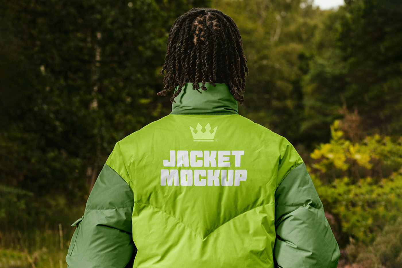 Men standing backward wearing green Winter Jacket Mockup with white strong typography design in the blurred forest in the background.
