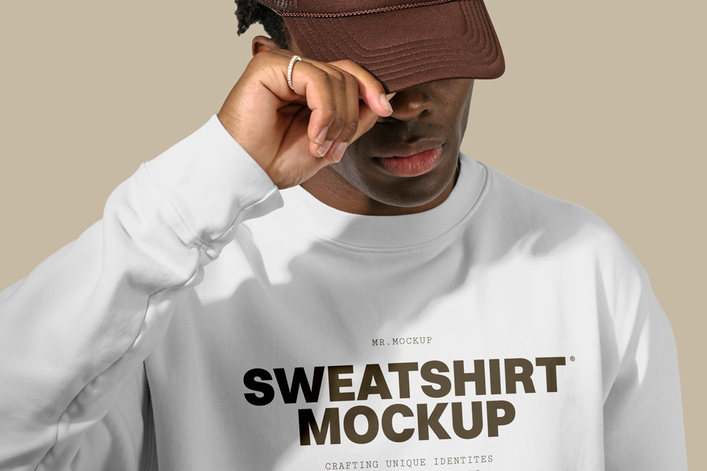 Standing men wearing a White Sweatshirt Mockup with a brown typography logo in front of the beige wall.
