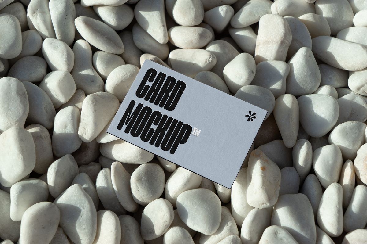 View from above, single outdoor business card mockup with blue and black colors and strong design, laying lies on the pebbles.