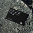 View from above, single outdoor business card mockup with blue and black colors, strong typography design, laying on massive stone.