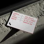View from above, single outdoor business card mockup with red and black colors, geometric typography design, laying on the concrete.