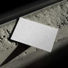 View from above, a single blank outdoor business card mockup laying on the concrete.
