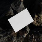 View from above, a single blank outdoor business card mockup laying on massive stone.