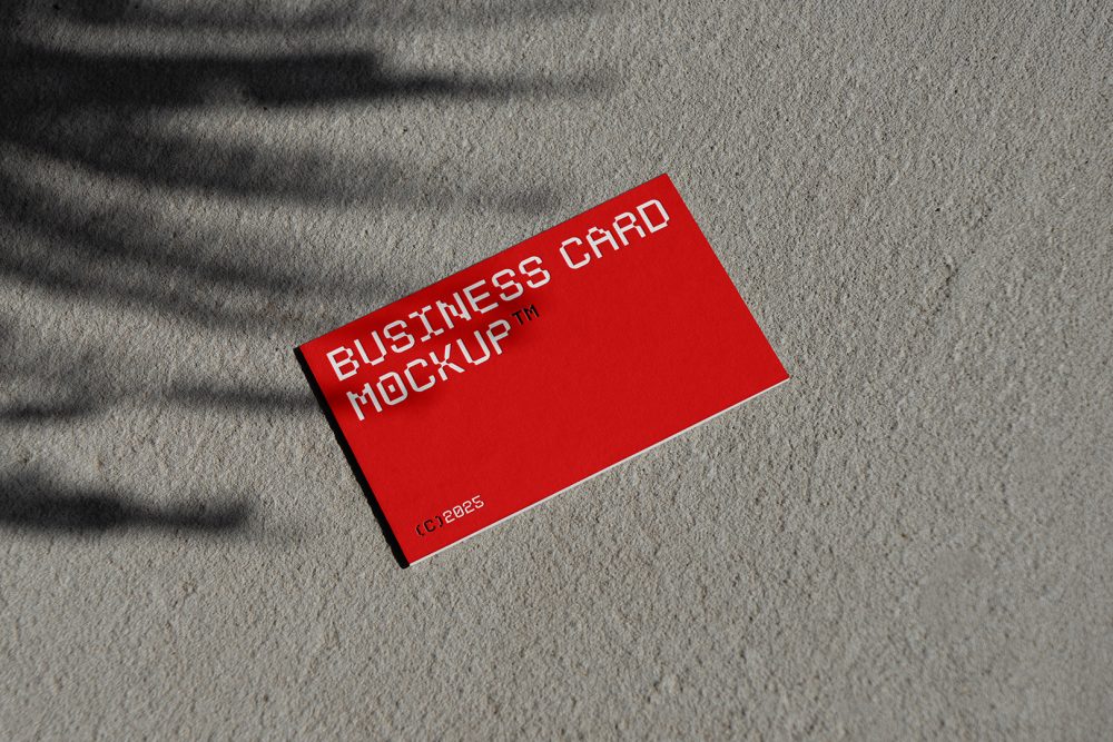 View from above, single outdoor business card mockup with red and white colors, geometric typography design, laying on concrete.