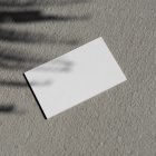 View from above, a single blank outdoor business card mockup laying on concrete.