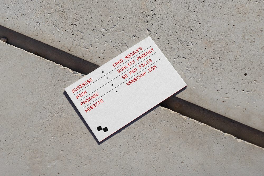 View from above, single outdoor business card mockup with red and black colors, geometric typography design, laying on concrete.