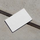 View from above, a single blank outdoor business card mockup laying on concrete.