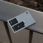 View from above, single outdoor business card mockup with blue and black colors, strong typography design, laying on the balcony railing.