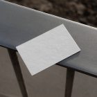 View from above, a single blank outdoor business card mockup laying on the balcony railing.