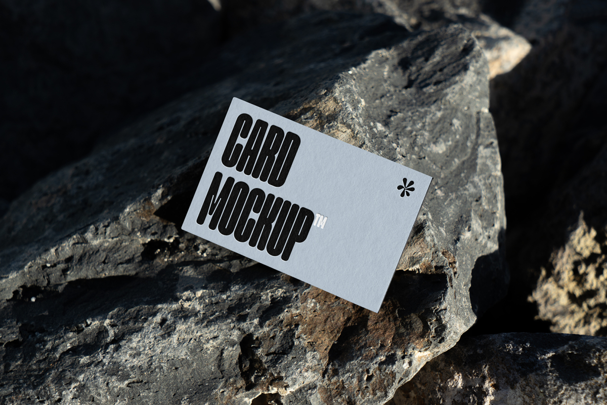 View from above, single outdoor business card mockup with blue and black colors, strong typography design, laying on massive stone.