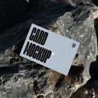 View from above, single outdoor business card mockup with blue and black colors, strong typography design, laying on massive stone.