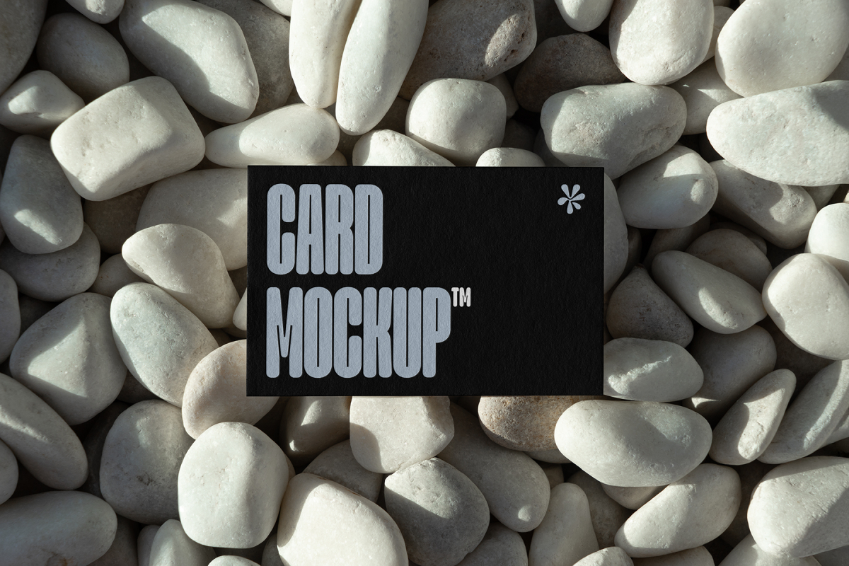 View from above, single outdoor business card mockup with blue and black colors and strong design, laying lies on the pebbles.
