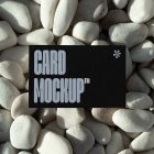 View from above, single outdoor business card mockup with blue and black colors and strong design, laying lies on the pebbles.