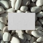 View from above, a single blank outdoor business card mockup laying lies on the pebbles.