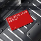 View from above, single outdoor business card mockup with red and white colors, geometric typography design, laying on an aluminum Rimowa brand suitcase.