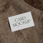 View from above, single outdoor business card mockup with green and gold colors, serif typography design, laying lies on a large root.
