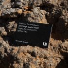View from above, single outdoor business card mockup with blue and black colors, strong typography design, laying on massive stone.