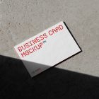 View from above, a single outdoor business card mockups with red and white colors, geometric typography design, laying on the concrete.