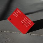 Front view, single outdoor business card mockup with red and white colors, geometric typography design, pressed into the crack of concrete.
